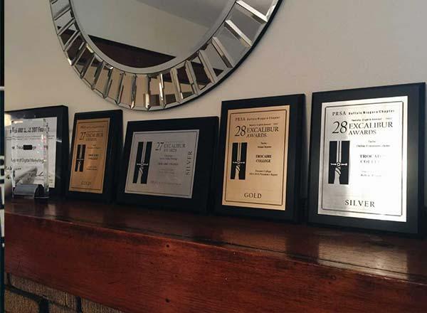 row of silver and gold awards on mantle under mirror