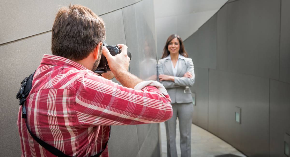 Man in red shirt taking photo of business woman