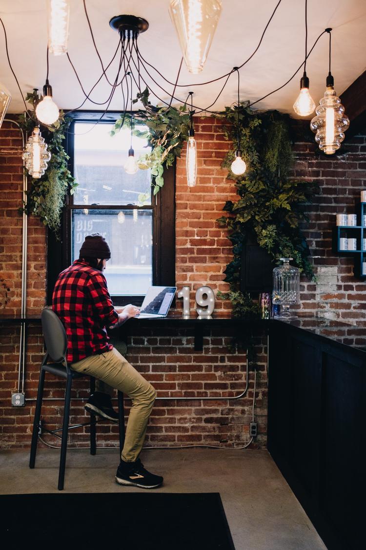 Man sitting on stool typing on laptop