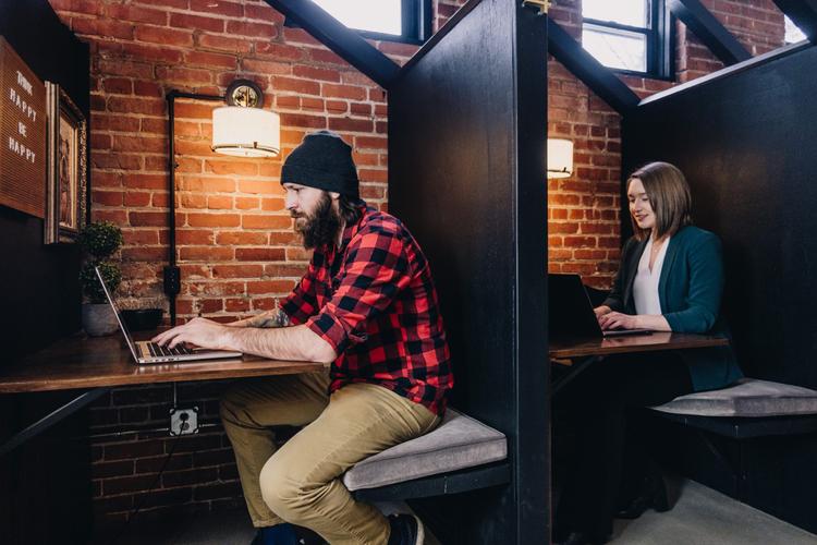 Two people sitting at desks typing on laptops