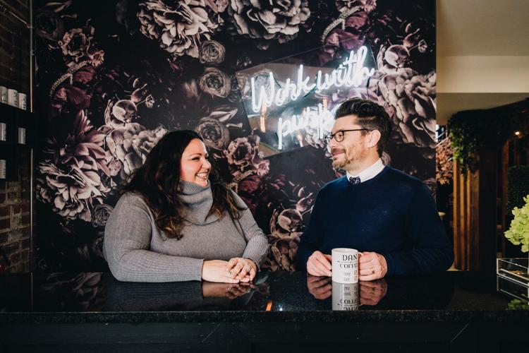 Man and woman standing at a bar smiling at one another