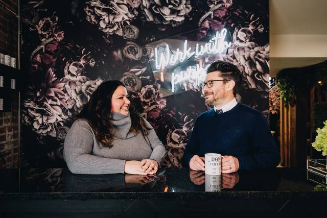 Man and woman standing at a bar smiling at one another