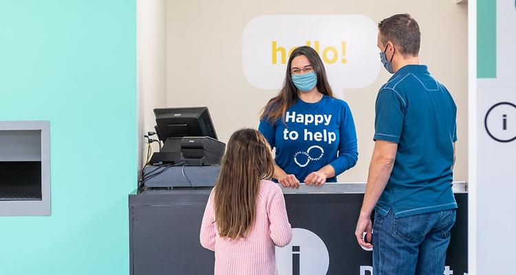 Child and Man Standing at Counter with Woman Employee