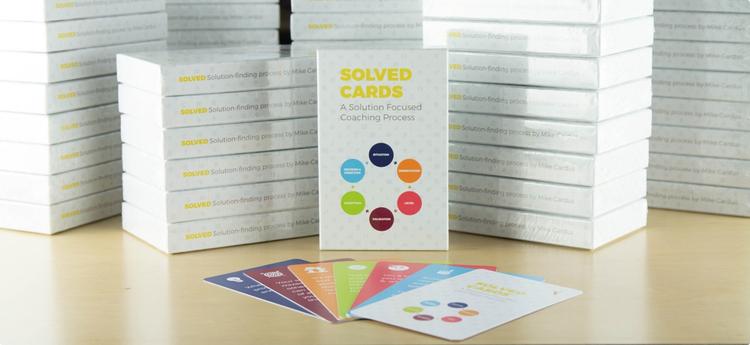 stack of white boxes with colorful cards splayed out in front